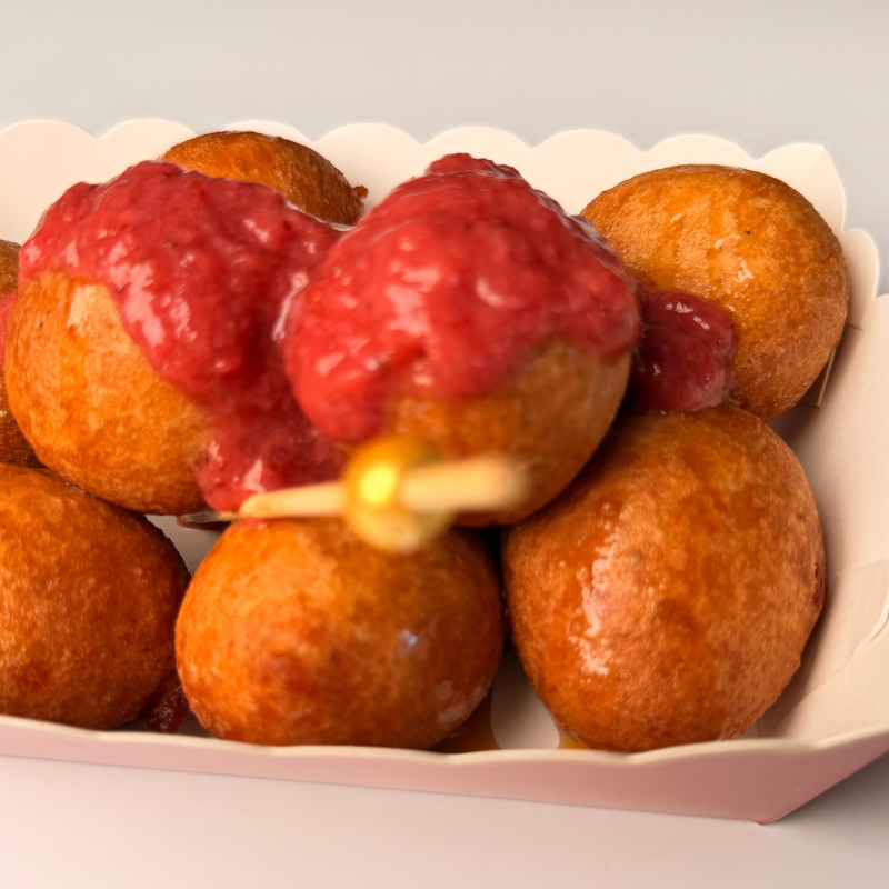 An assortment of golden puff-puff boxes topped with strawberry, orange marmalade, and pistachio